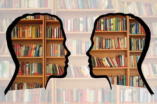 Outlines of two people in profile facing each other with bookshelves as a background.