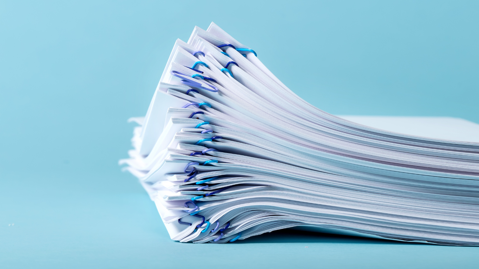 Image of stack of papers on blue background. 