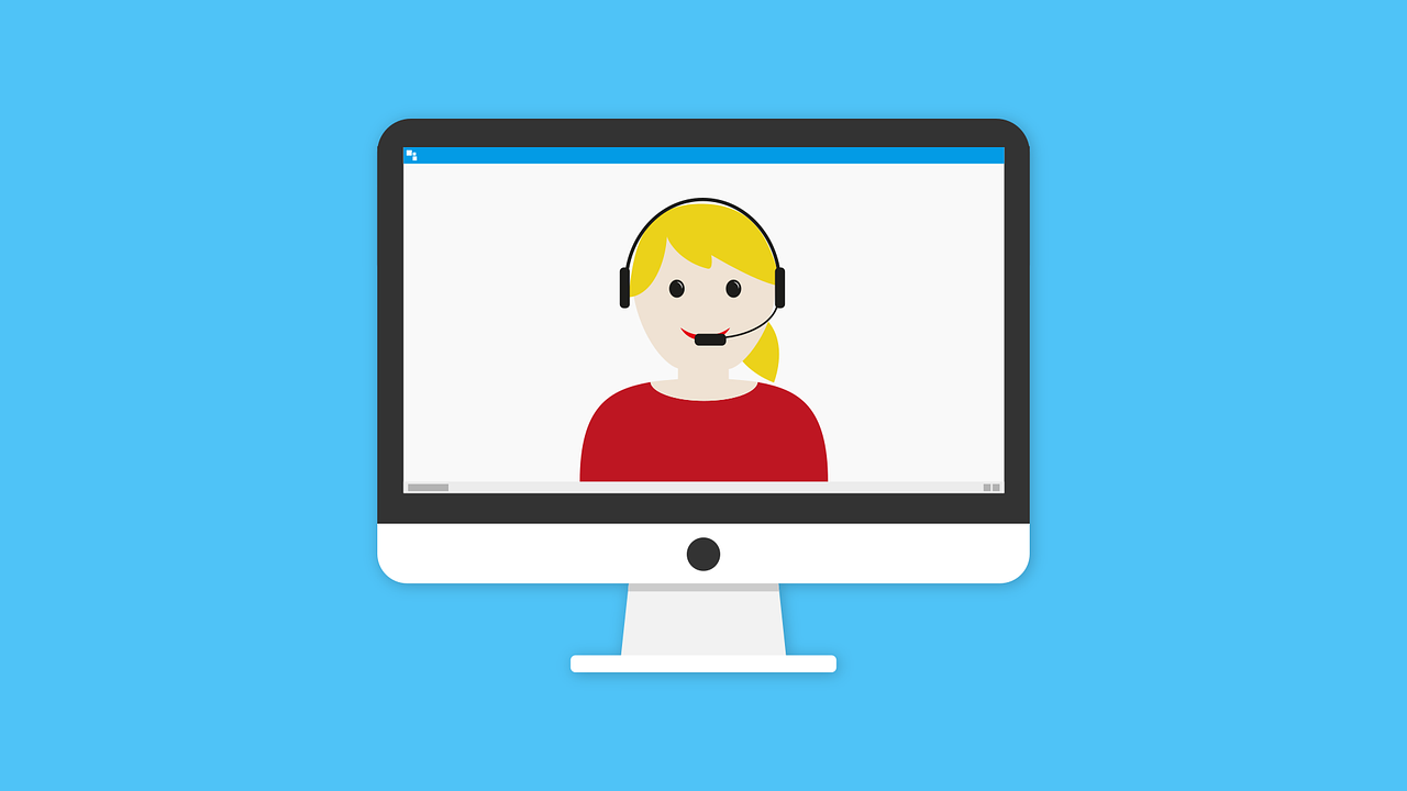 A computer monitor displaying a smiling woman wearing a headphone and microphone headset.