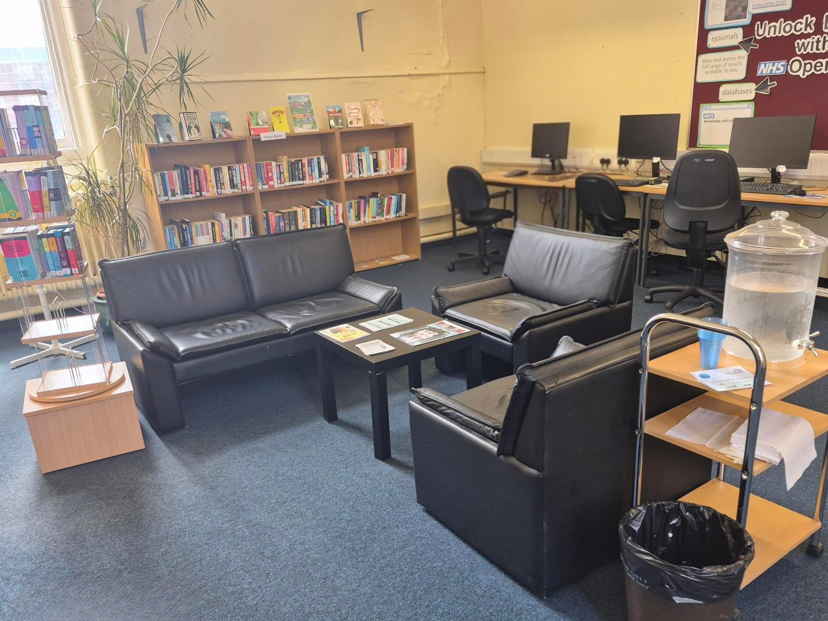 computers, sofa seating and fiction book shelves on back wall