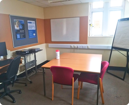 room with large desk, chair, computer, projector and flipchart