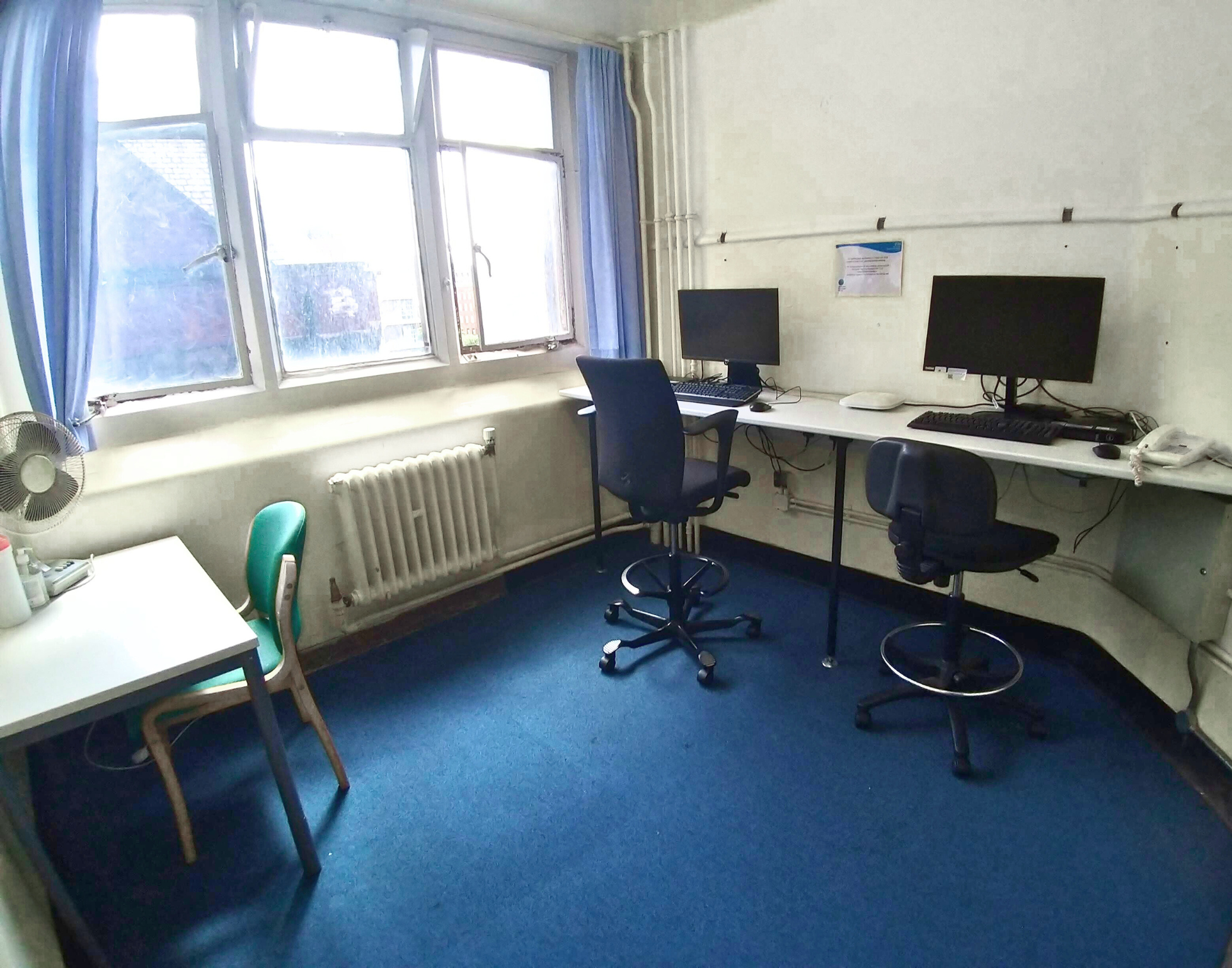 Small room with two pcs with high computer chairs, next to a high table.